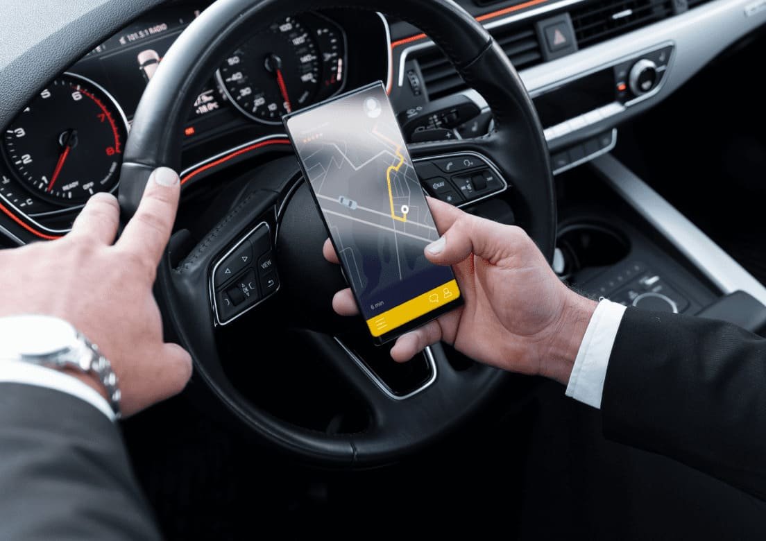 Close view of a navigation screen held beside a car steering wheel