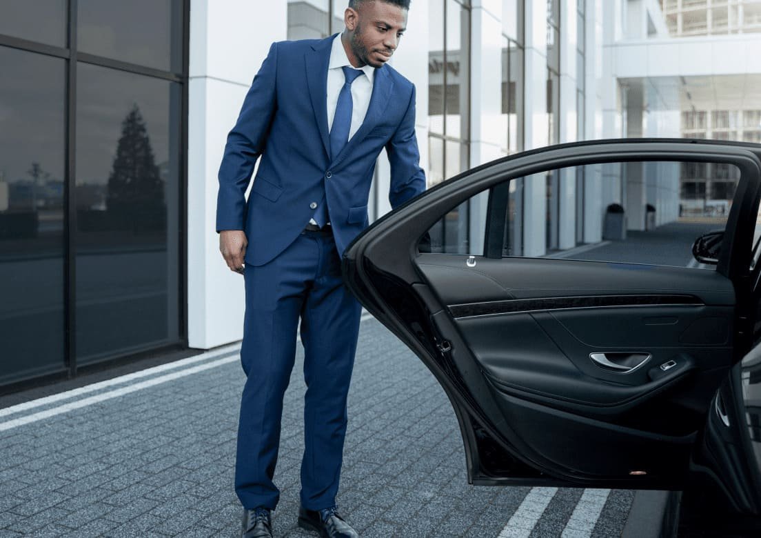 Man wearing a blue suit standing beside an open dark car door