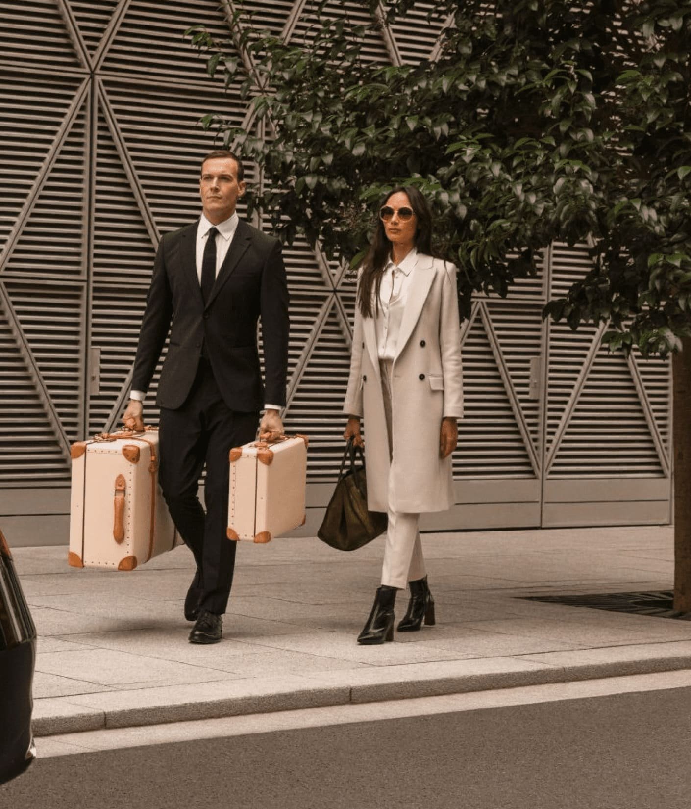 Two travellers walking with rolling suitcases outside a modern building