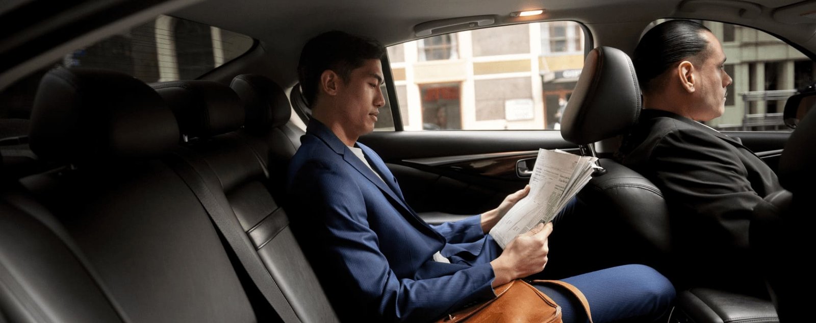 Passenger reading documents in the rear seat while a driver sits in front