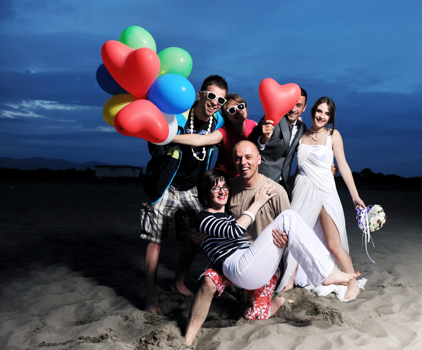 Group celebrating on a beach with colourful balloons