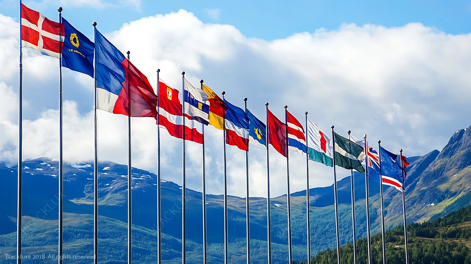 Row of international flags with mountains in the background