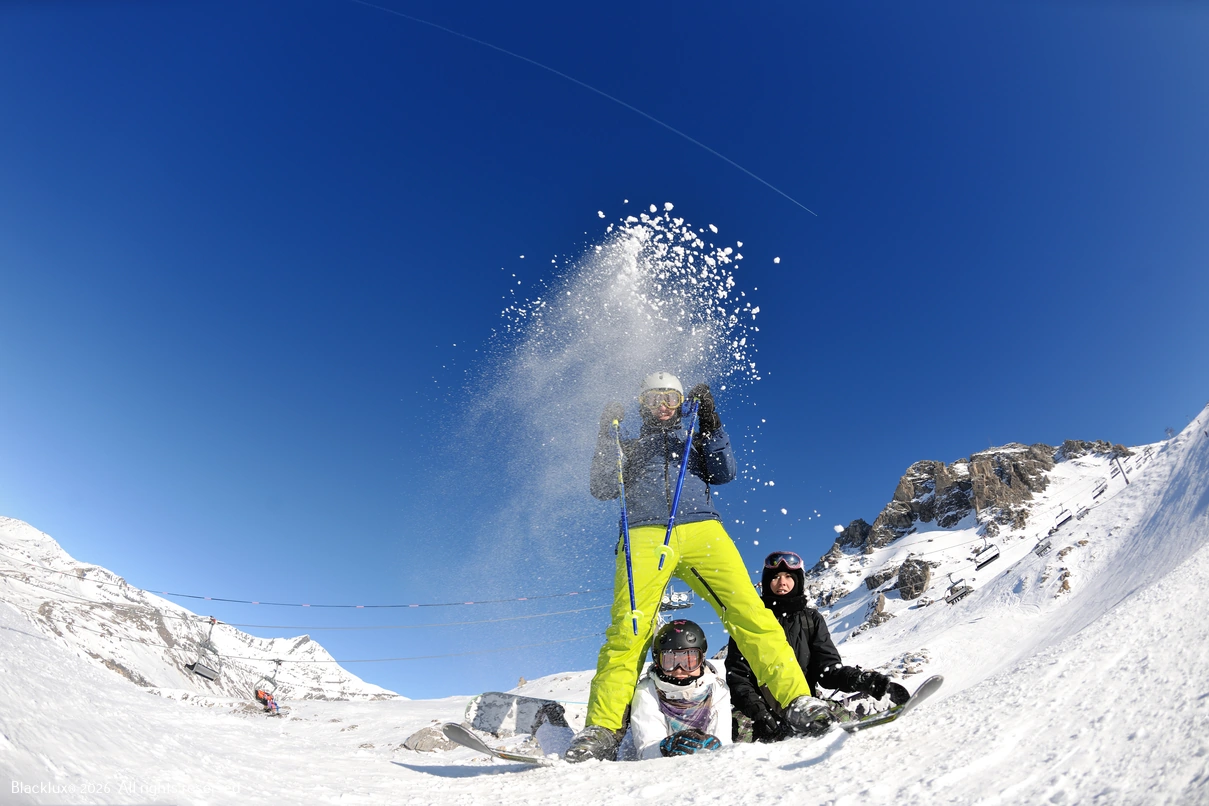 Wintersportler wirft Schnee vor einem blauen Himmel in die Luft