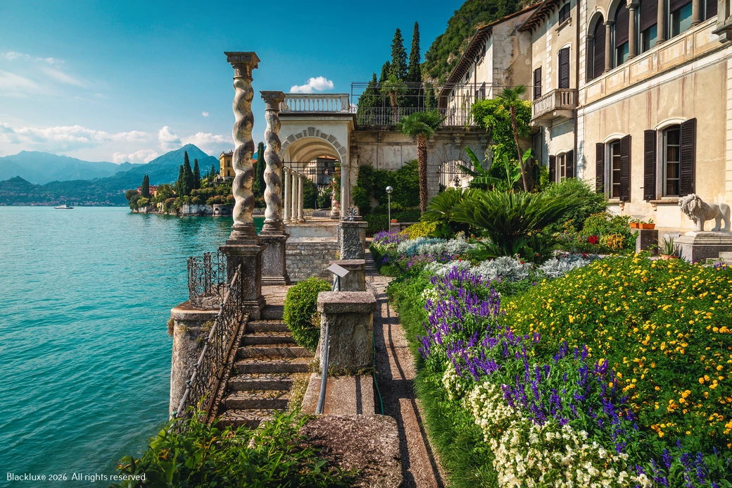 Lakeside villa terrace with twisted stone columns, steps, iron railings and colourful flowerbeds