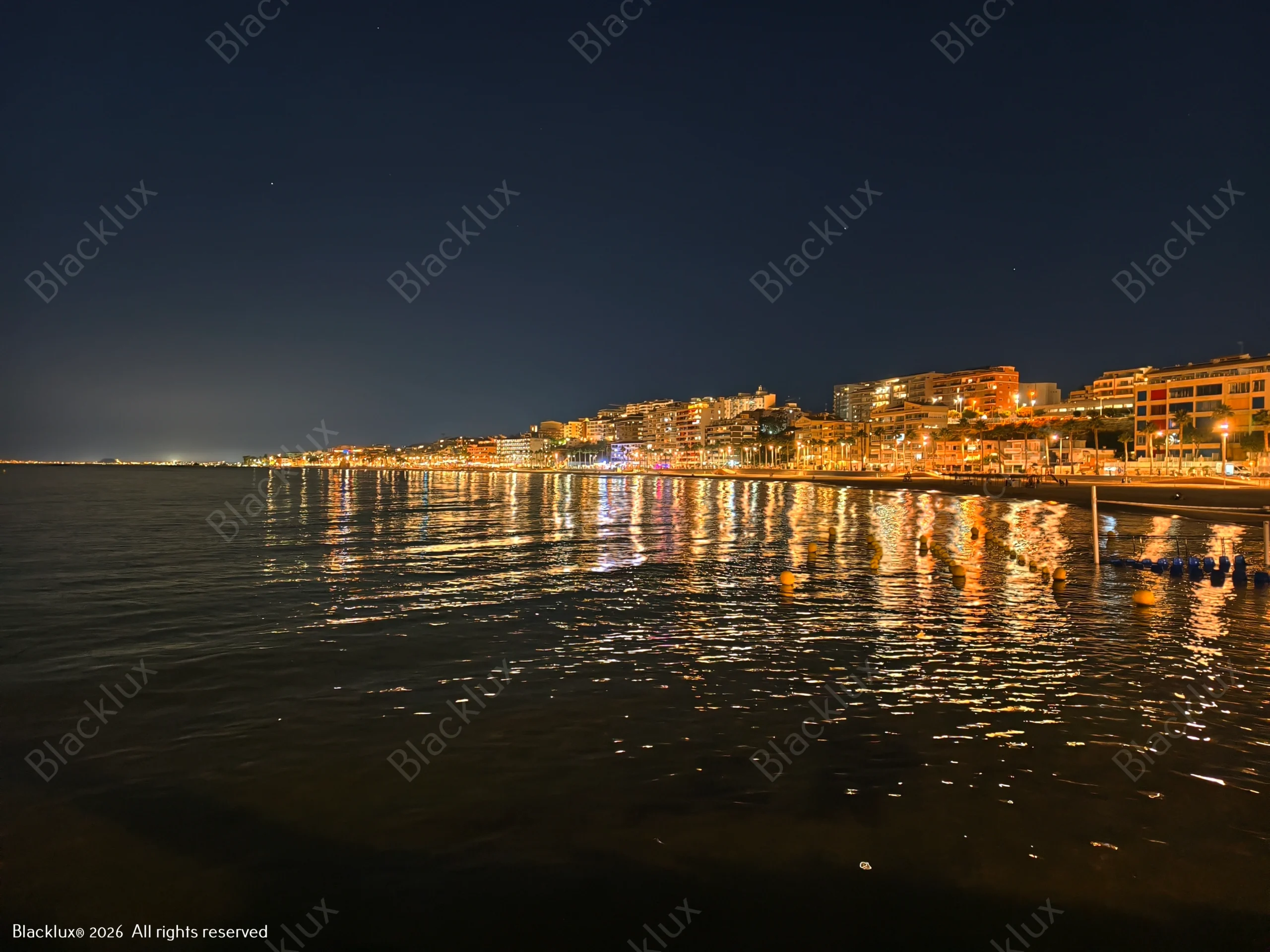 Coastal lights reflected on dark water after sunset