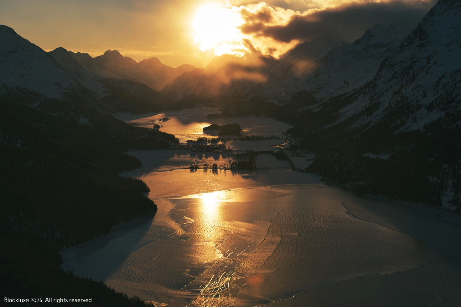Sunlight reflected on an alpine lake between dark mountain slopes