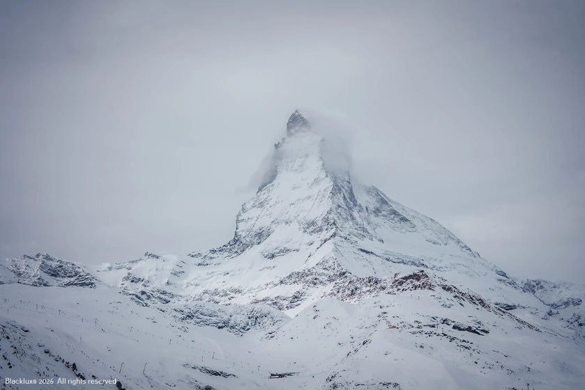 Snow-covered Matterhorn peak partly obscured by grey cloud