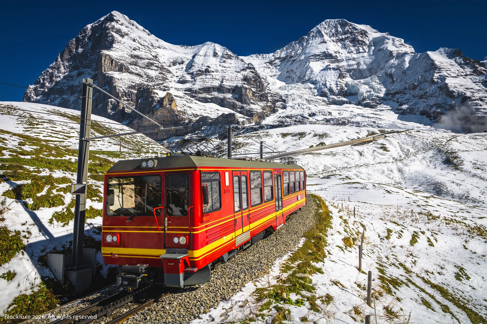 Red mountain train on a railway beside snow-covered slopes