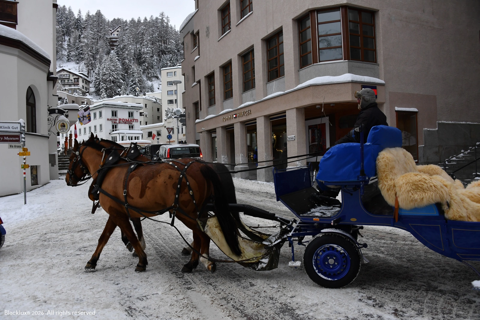 Carrozza trainata da cavalli lungo una strada con edifici e neve sullo sfondo