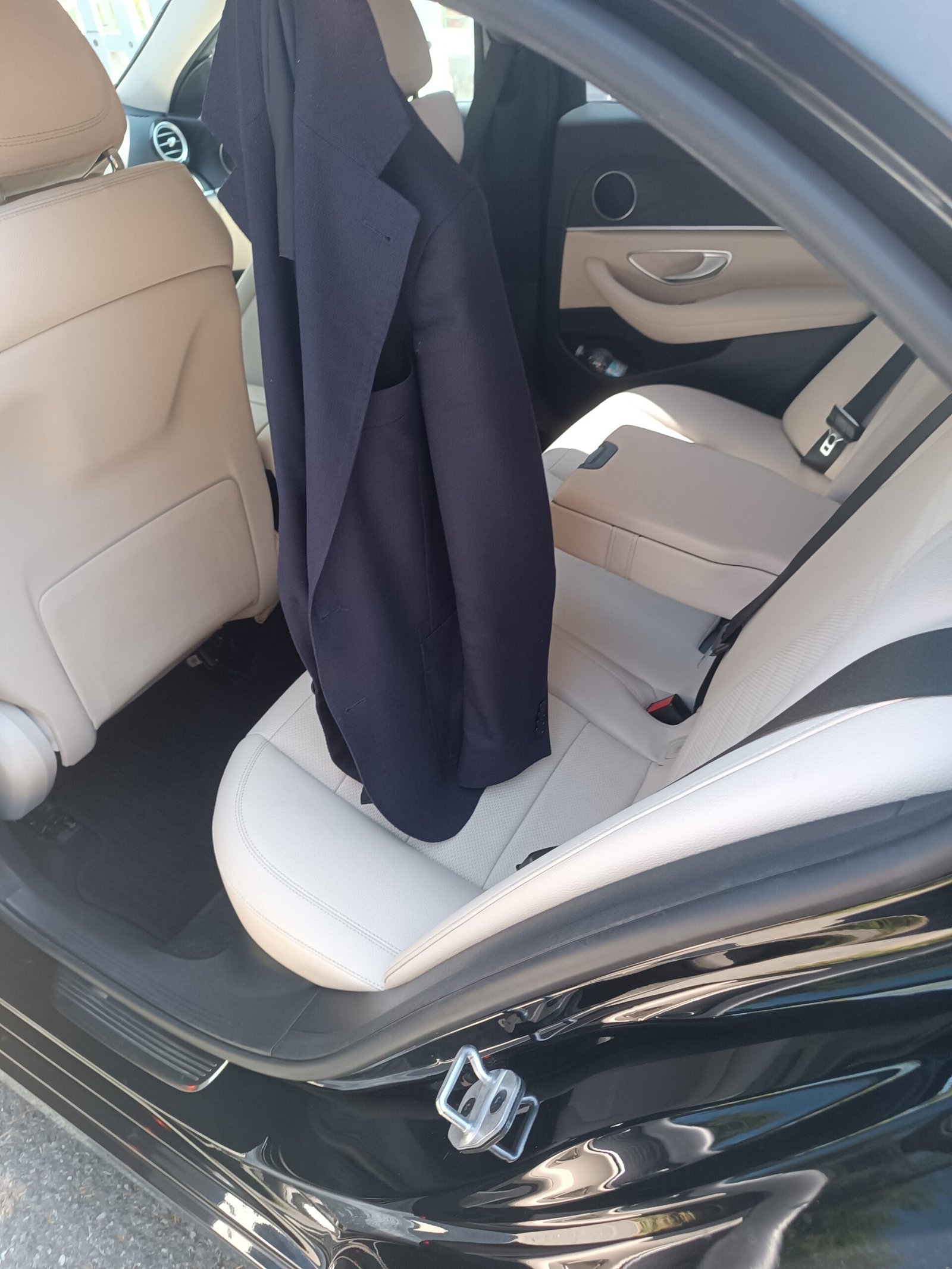 Light-coloured rear passenger seat and open door with a jacket hanging inside