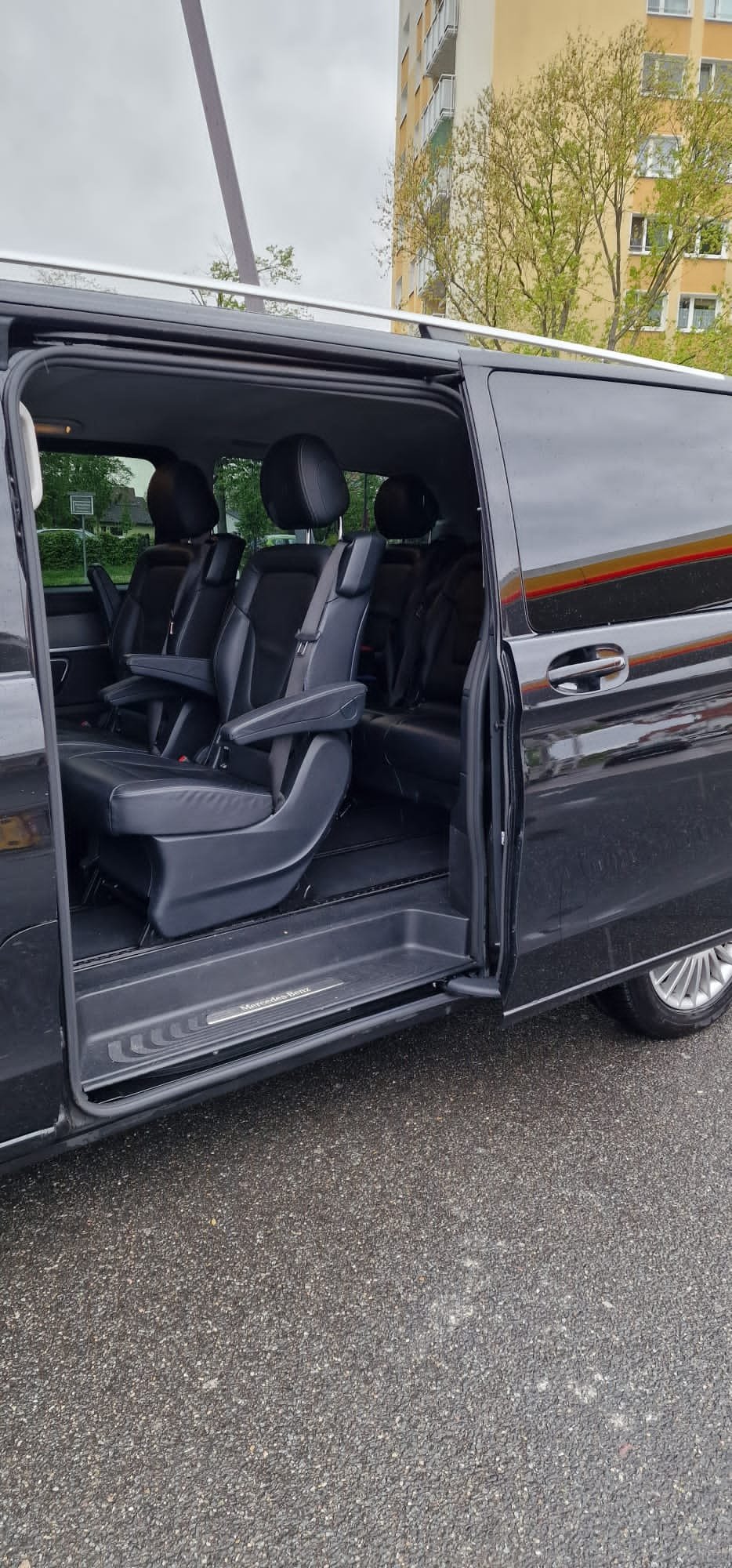Open sliding door of a black van showing passenger seats and the entry step