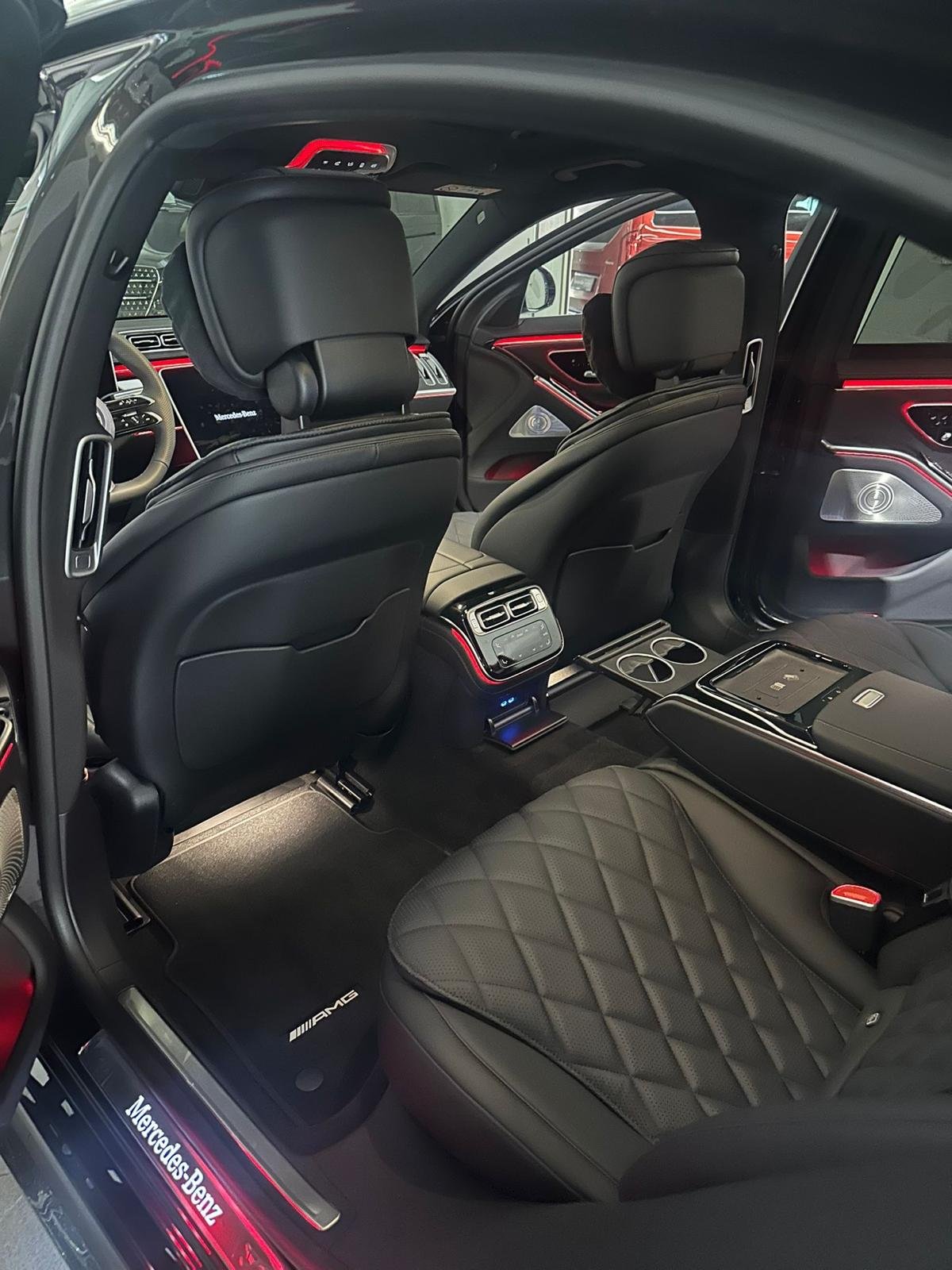 Dark quilted passenger seats and red ambient lighting seen through an open car door
