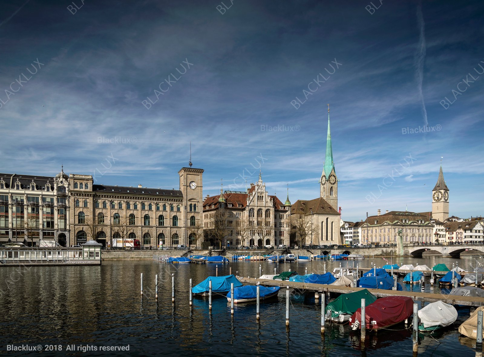 Zurich waterfront on the Limmat with covered boats, historic buildings and church towers