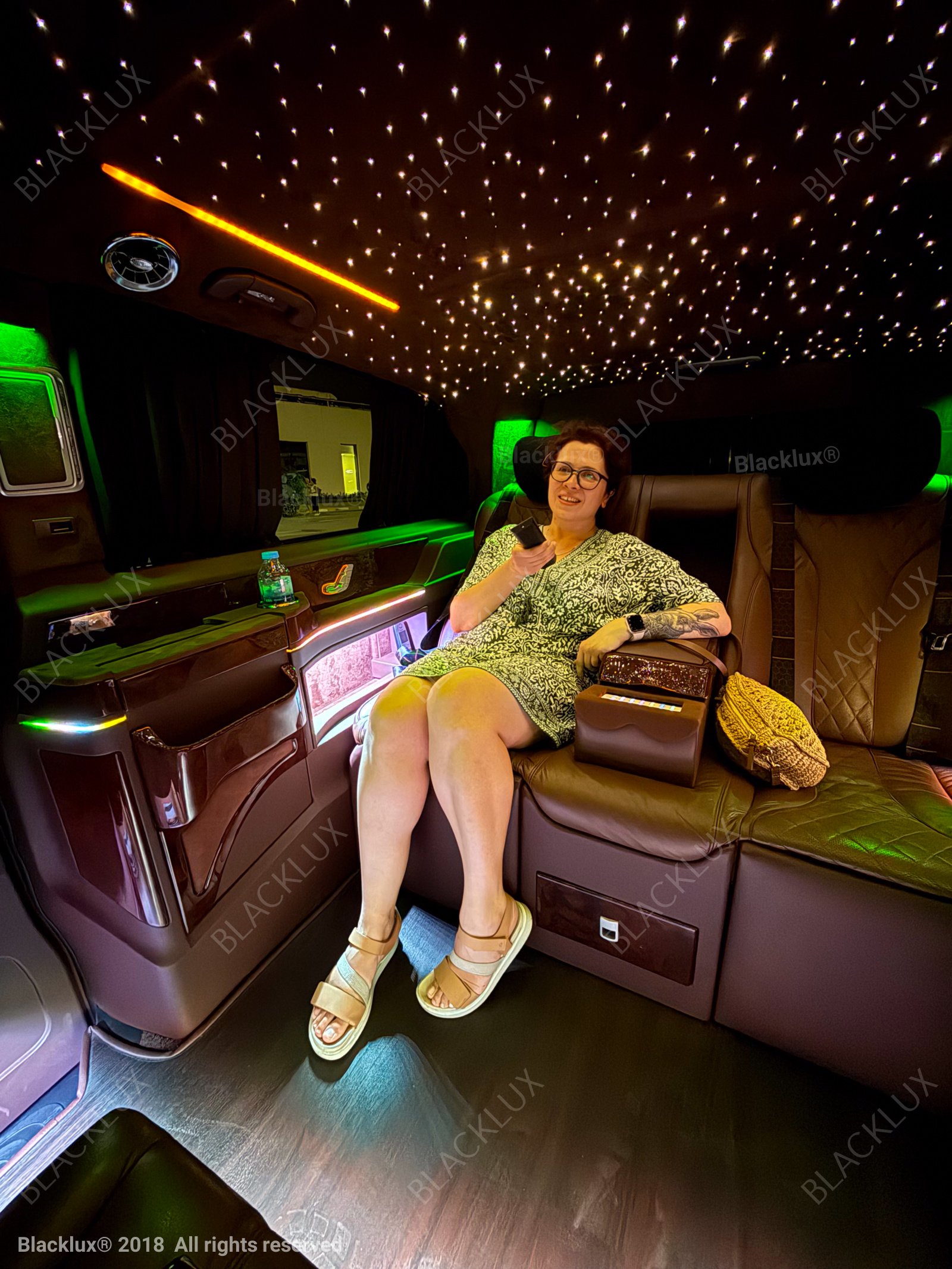 Woman seated in a softly illuminated luxury vehicle cabin with warm decorative lighting