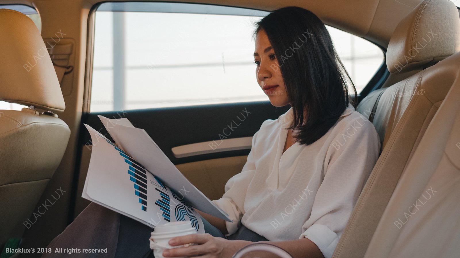 Passenger reviewing printed charts and documents in a light rear cabin