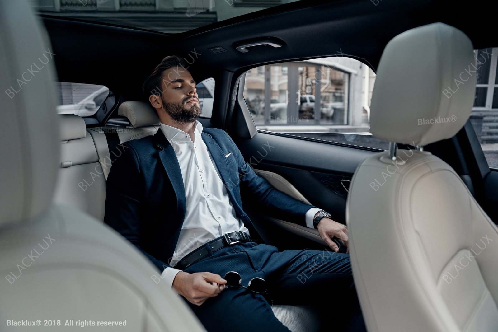 Traveller reclining in a light-coloured rear car seat with eyes closed