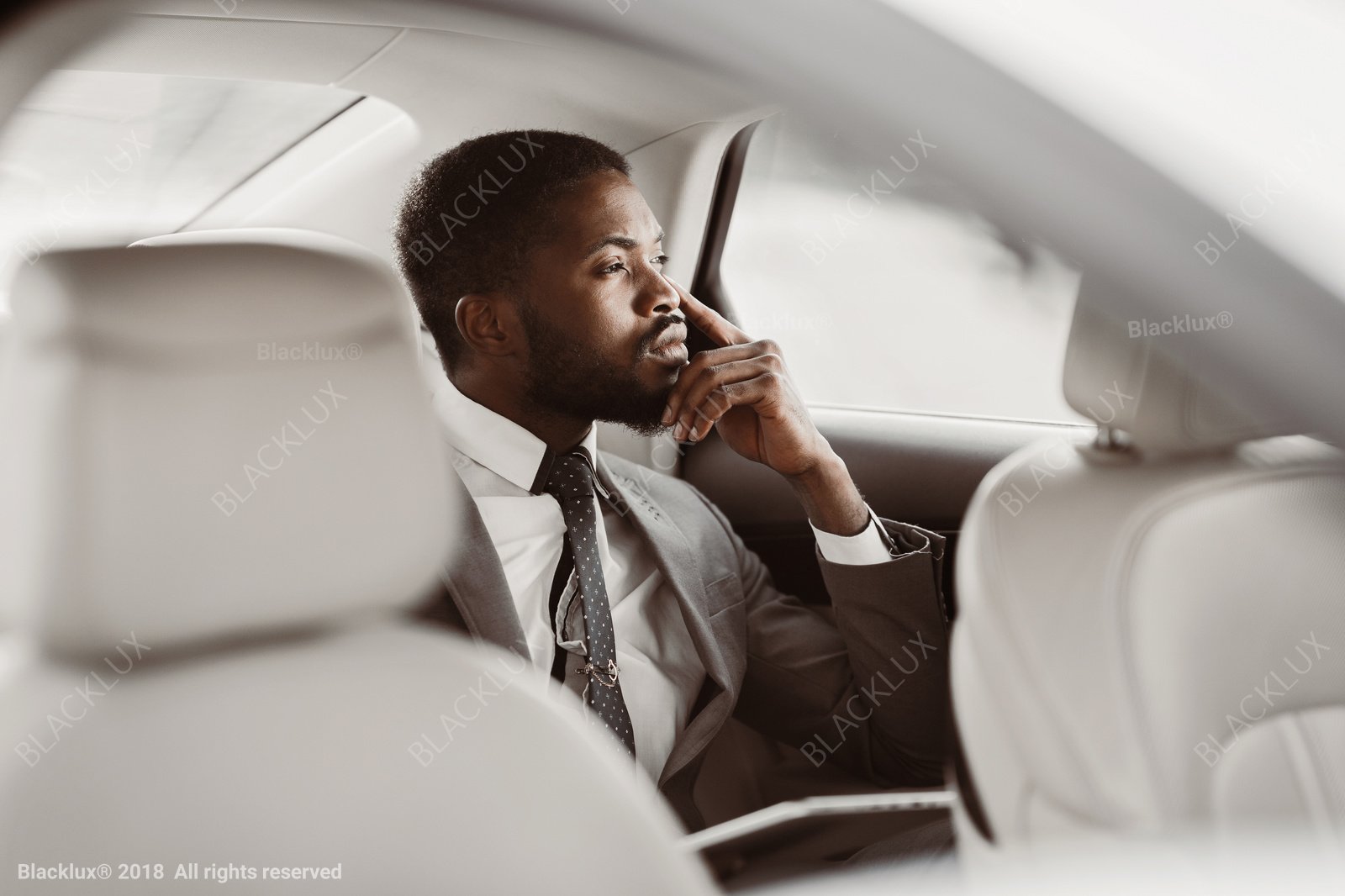Passenger in a suit looking through the window from a light-coloured rear cabin