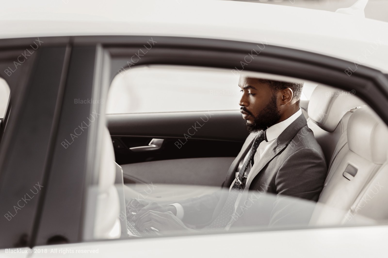 Side view of a man wearing a light suit seated in a cream-coloured passenger cabin