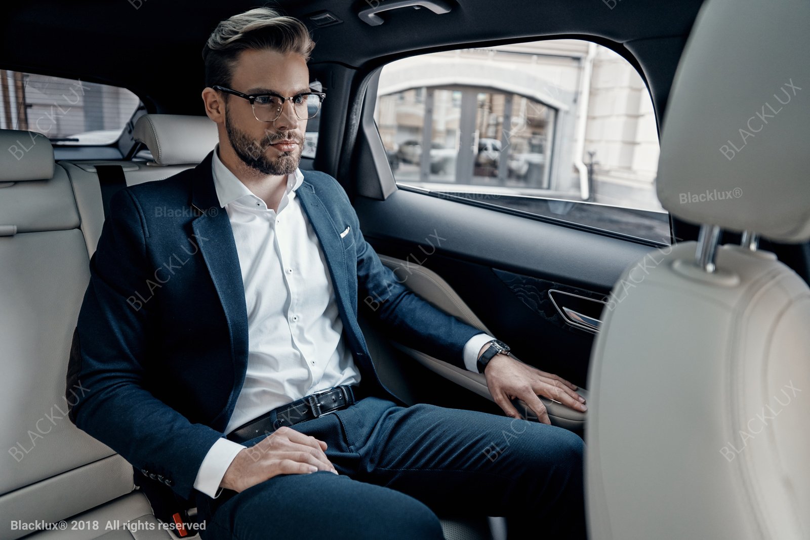 Man in a blue suit seated in a spacious light-trimmed passenger cabin