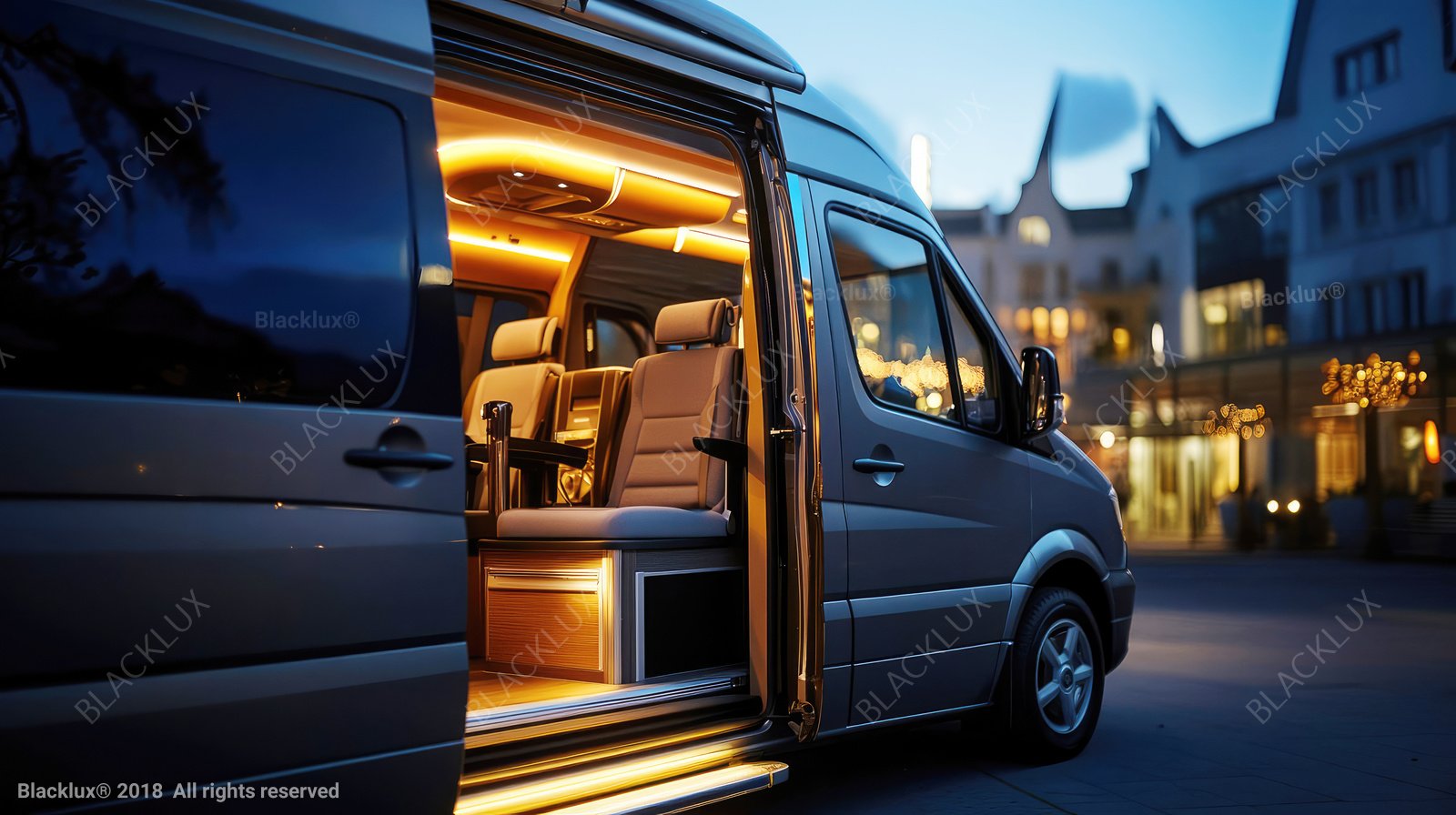 Warmly illuminated passenger cabin seen through the open sliding door of a dark luxury van
