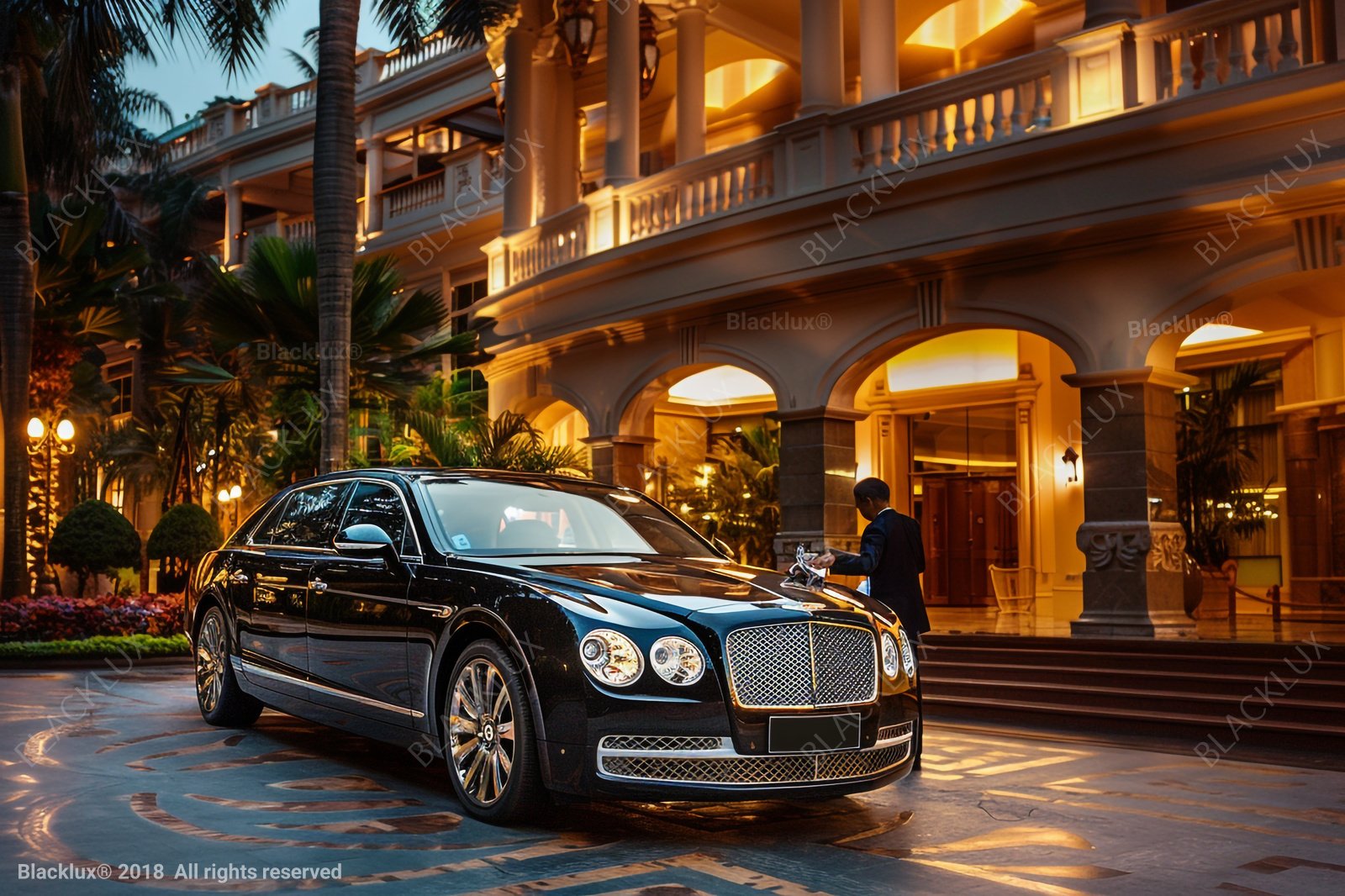 Black sedan outside an illuminated hotel entrance with stone arches and palms