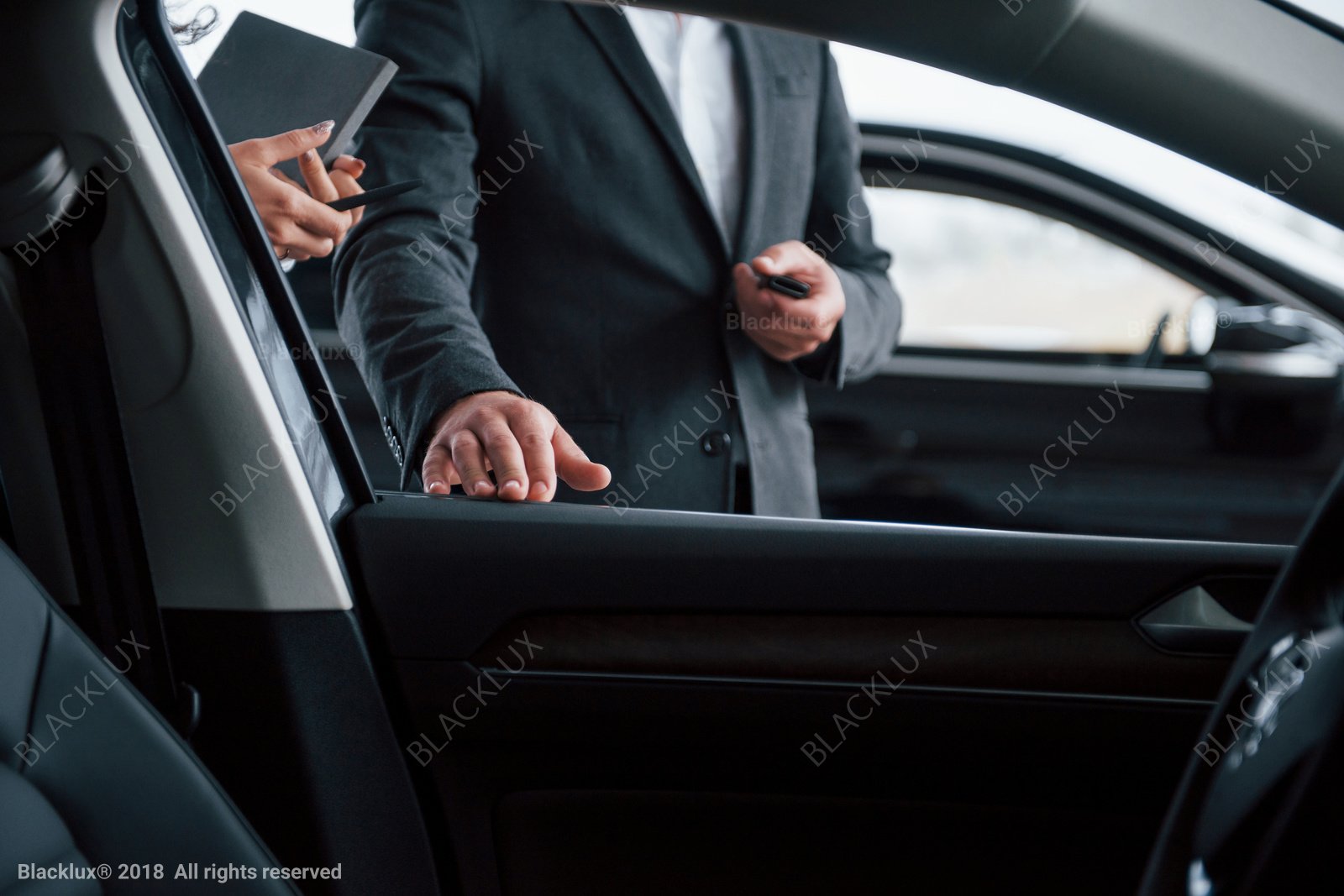 View from inside a vehicle as a suited person demonstrates the open door and cabin