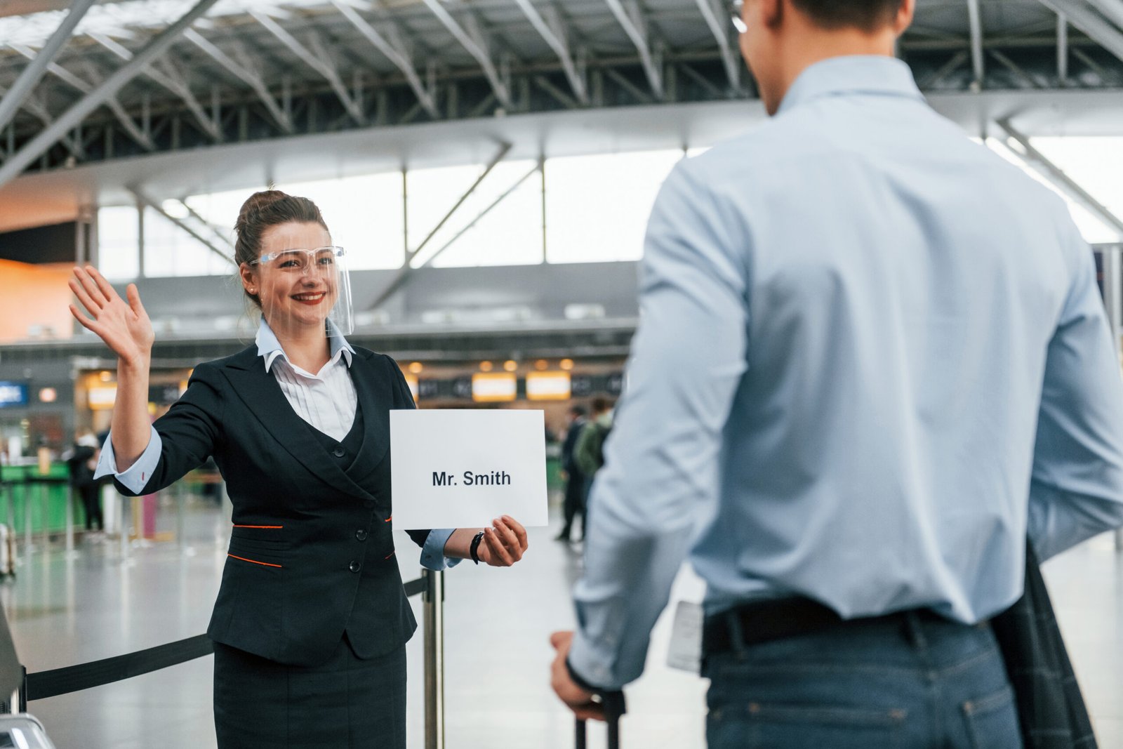 Airport representative holding a passenger name sign in a bright arrivals hall