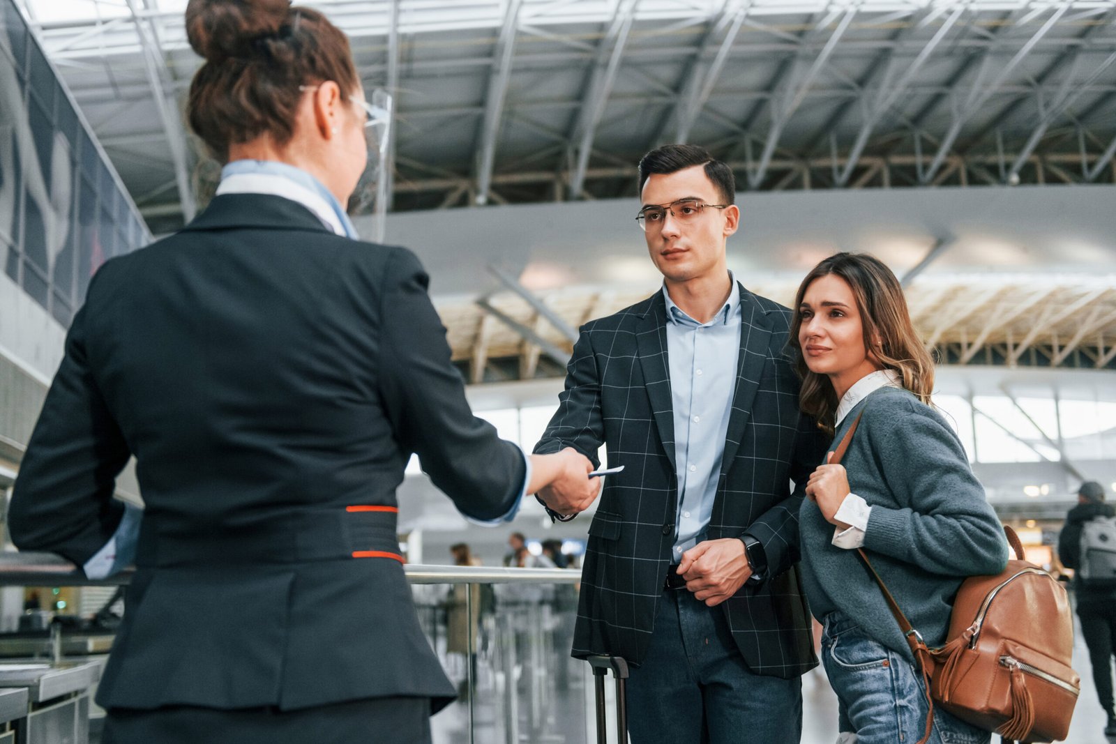 Three adults greeting one another inside an airport terminal